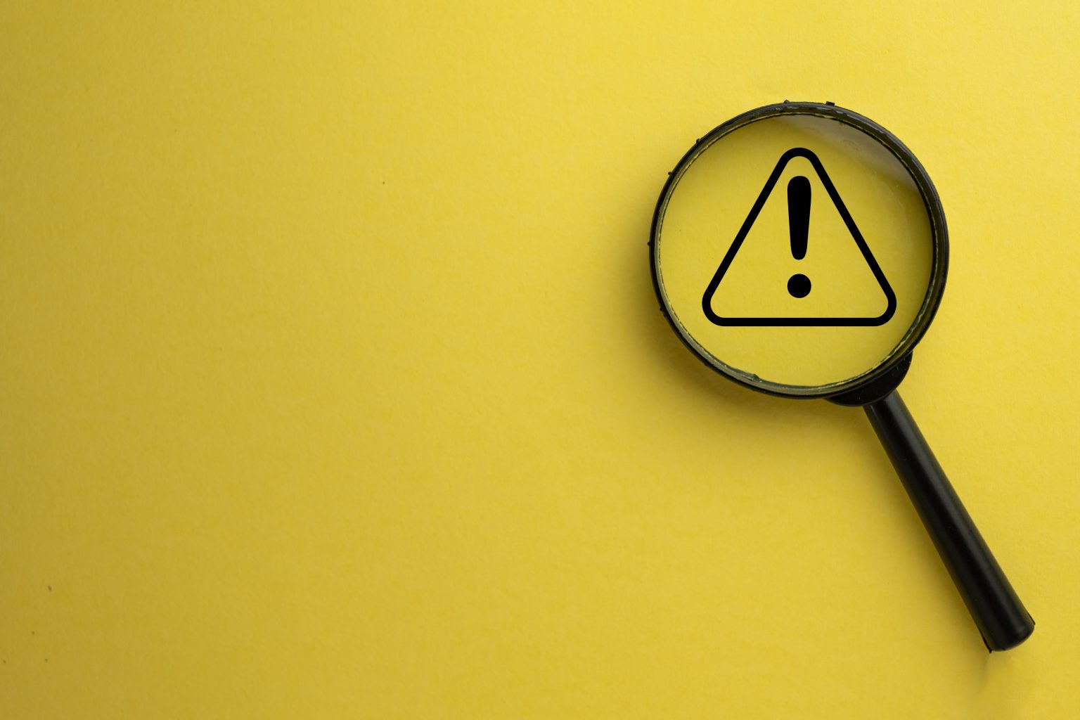 Magnifying glass over caution sign  