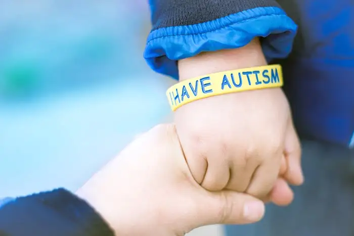 a photograph of a small child's wrist with a bracelet saying I have autism