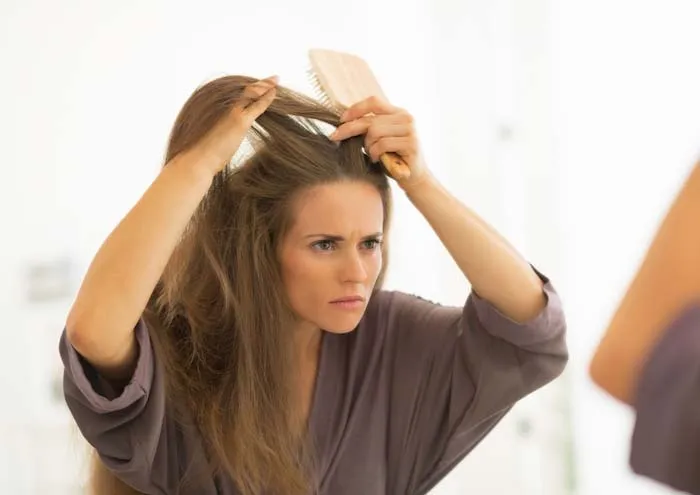 A woman with dandruff looking into a mirror. | Best Remedies for Dandruff