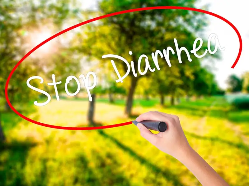 Woman writing Stop Diarrhea with a marker over blurred natural background. Diarrhea remedies