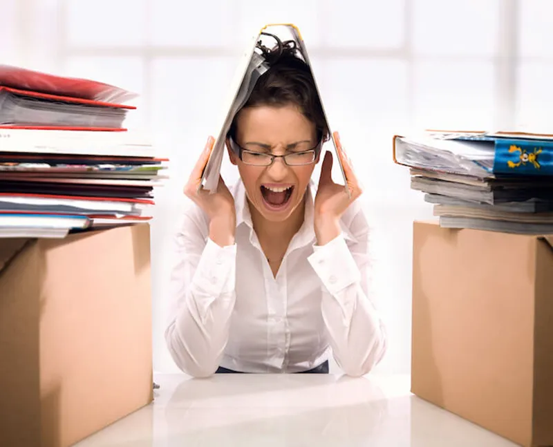 Overwhelmed woman stressed with piles of paperwork