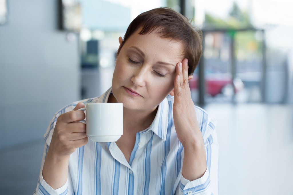 Woman feeling stressed, drinking tea