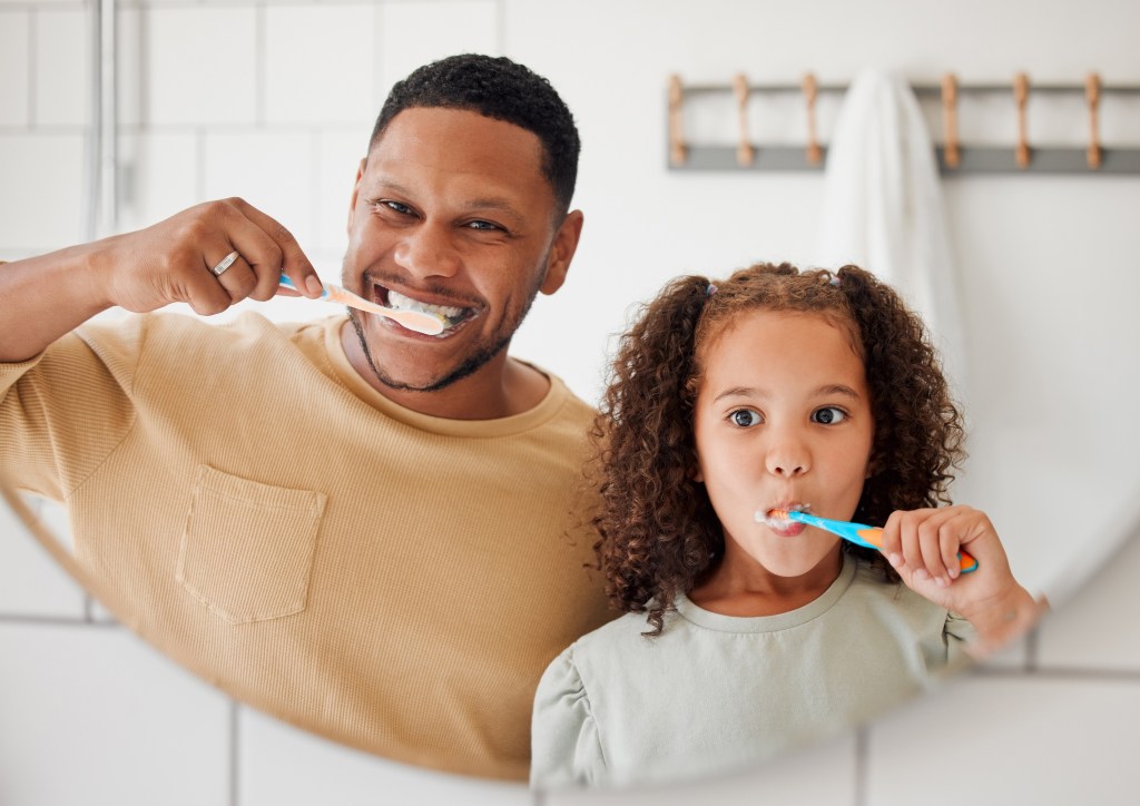 Father and daughter brushing teeth