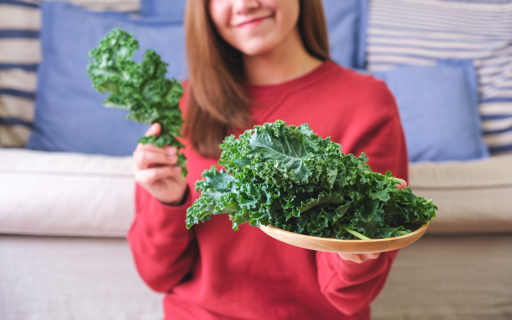 woman holding plate of kale