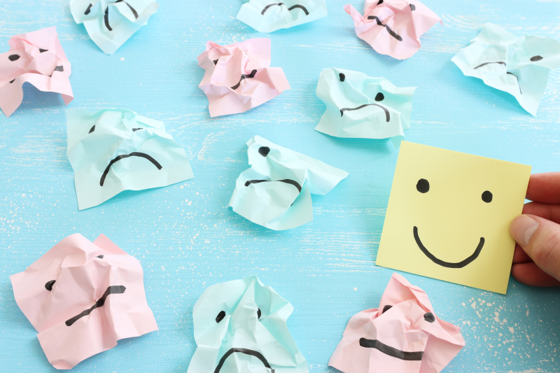 Happy face note among sad face crumpled papers.