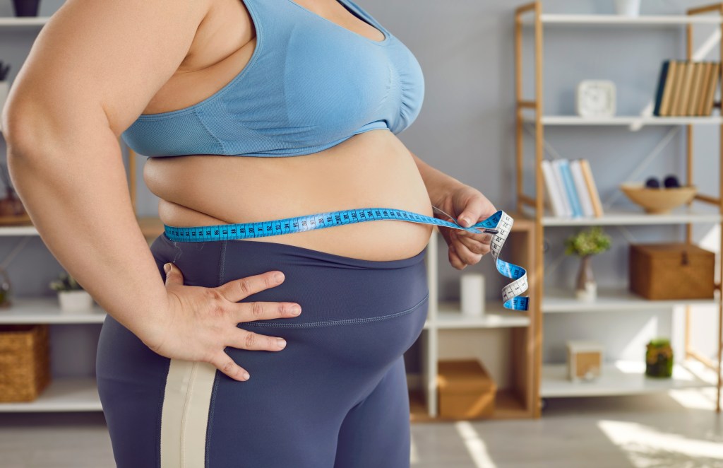 Overweight woman measuring her stomach
