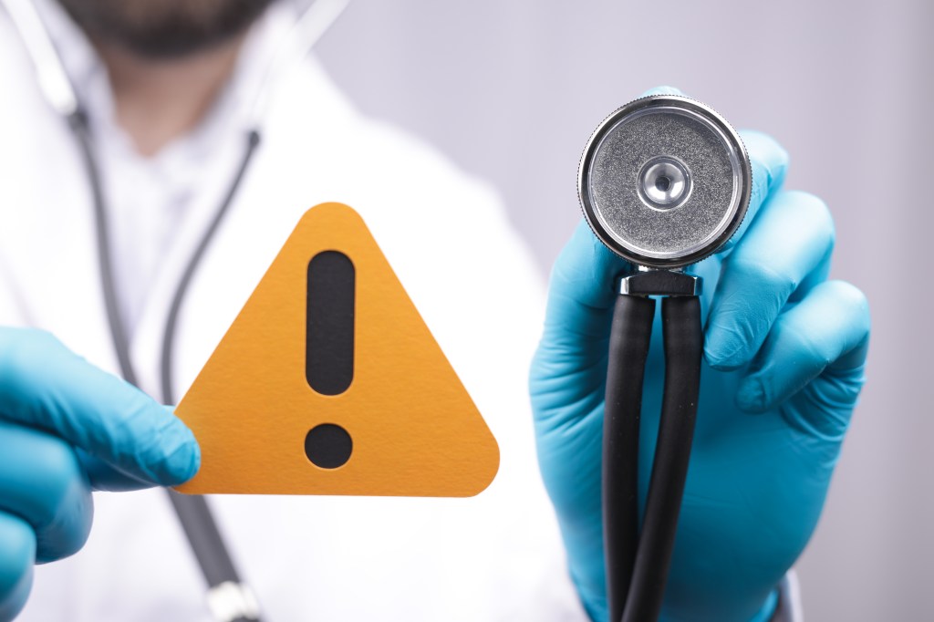 Doctor holding an exclamation sign and a stethoscope