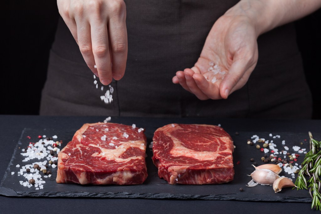 Hand sprinkling sea salt on meat