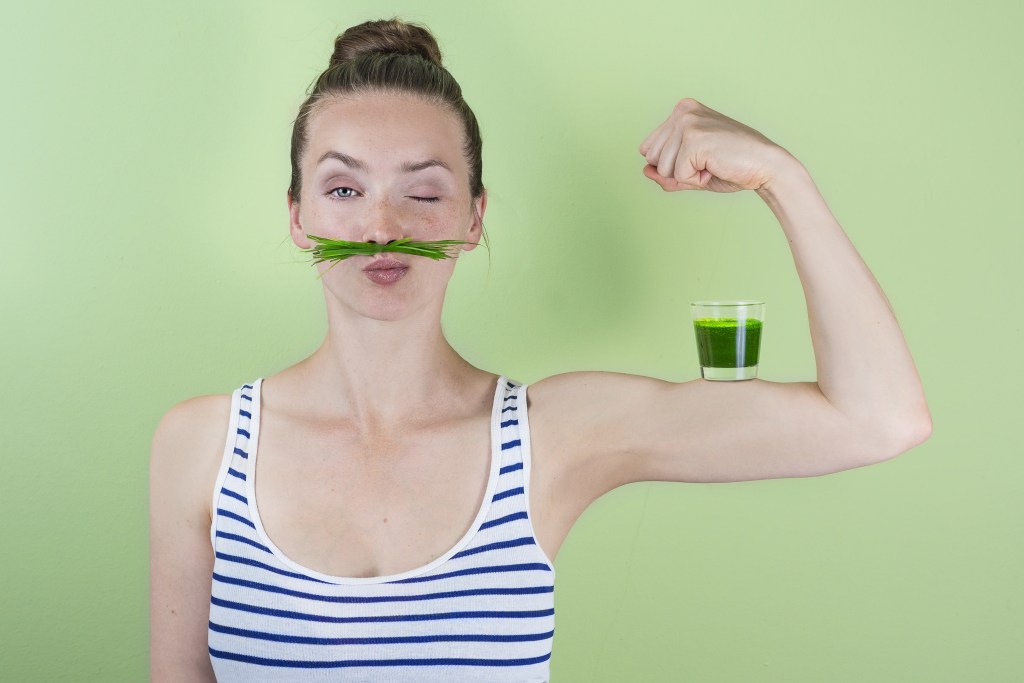Strong woman with a wheatgrass juice shot
