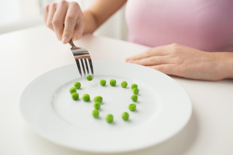 Hand with fork forming a heart with peas