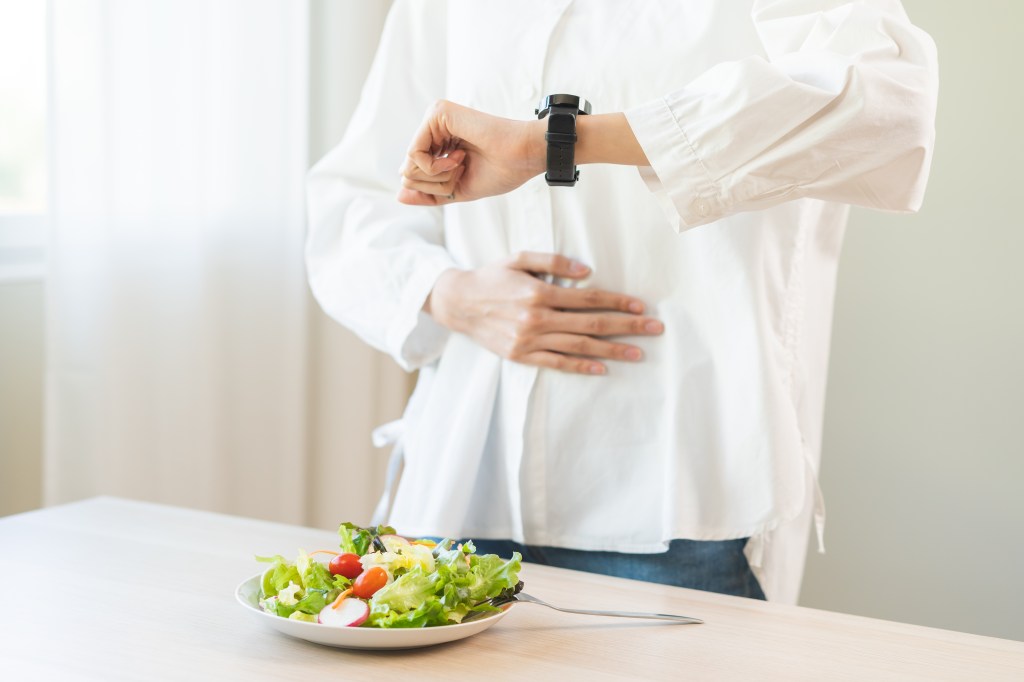 holding belly while looking at a watch