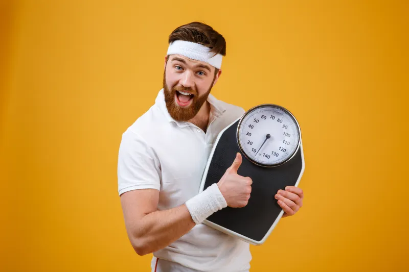 Happy man holding scale