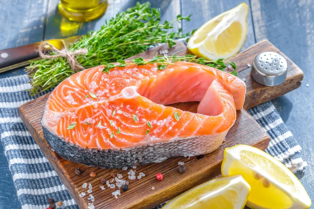 Piece of salmon with lemons and herbs on a cutting board