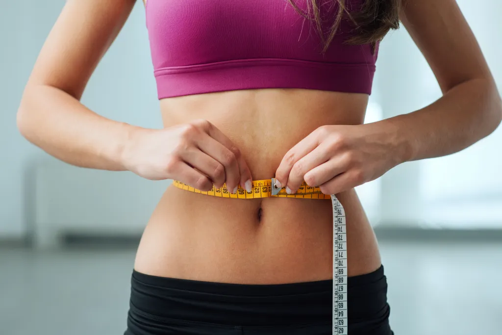 Fit woman measuring waistline