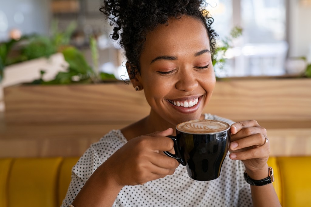 Woman smiling while holding a cup of coffee
