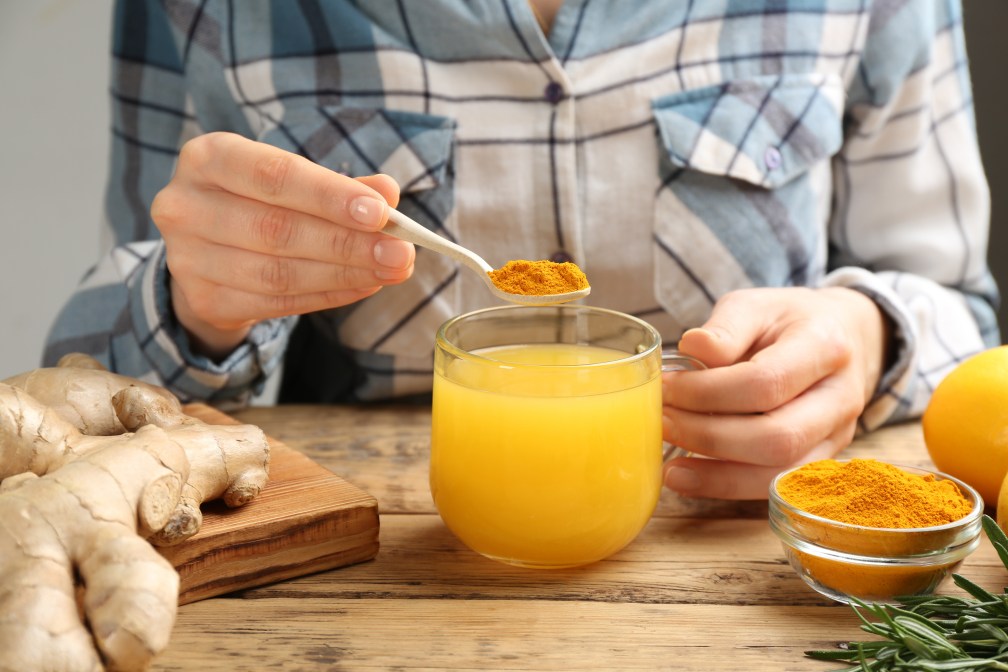 Woman adding turmeric powder to drink