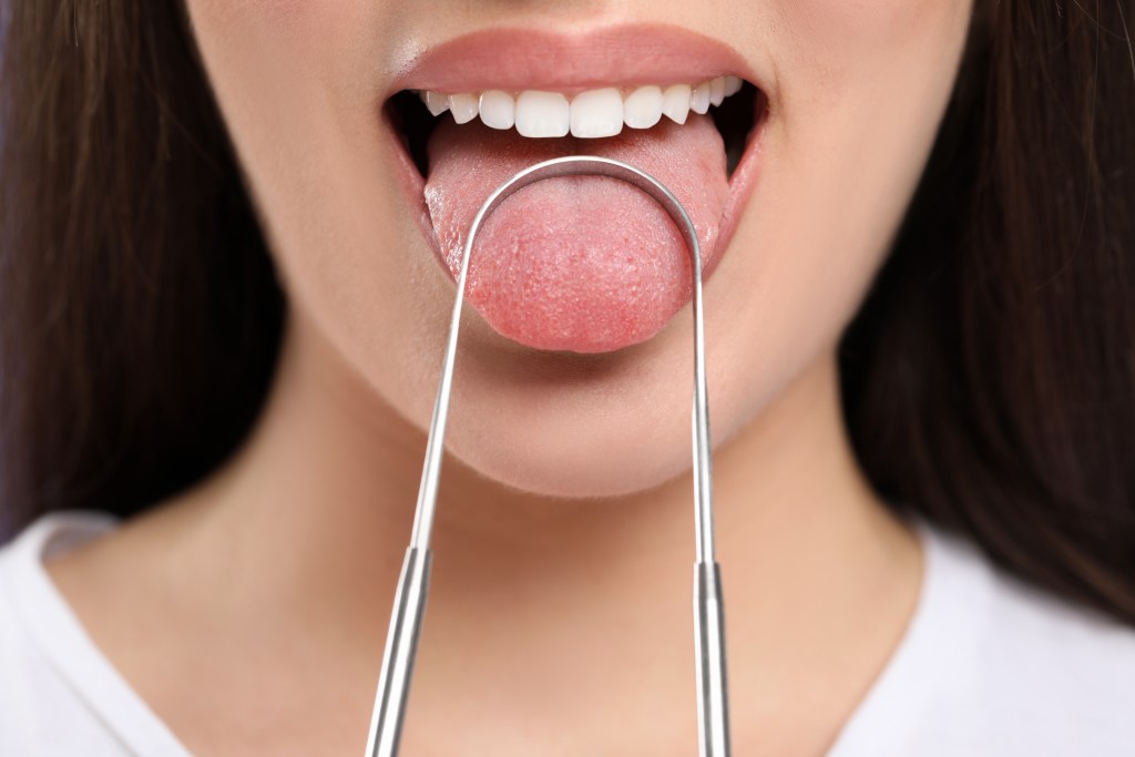 Woman using tongue scraper