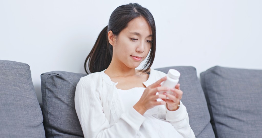 Woman checking supplement label 