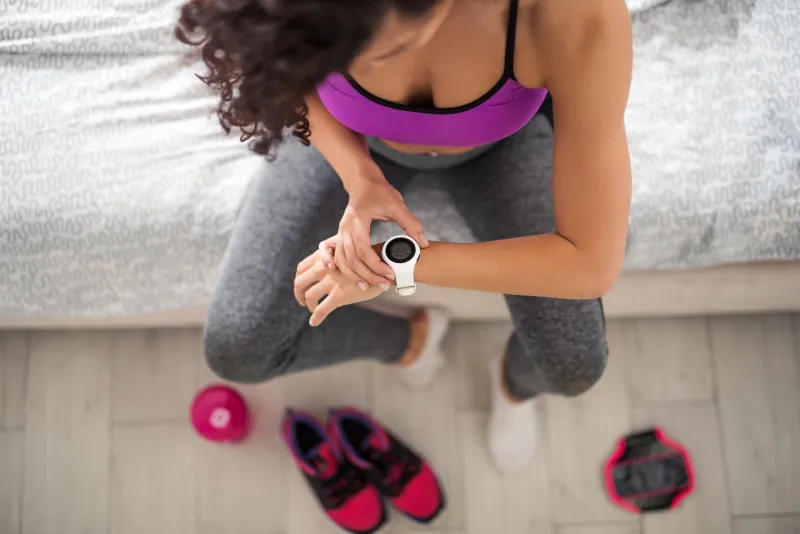 Woman checking smartwatch before workout at home.