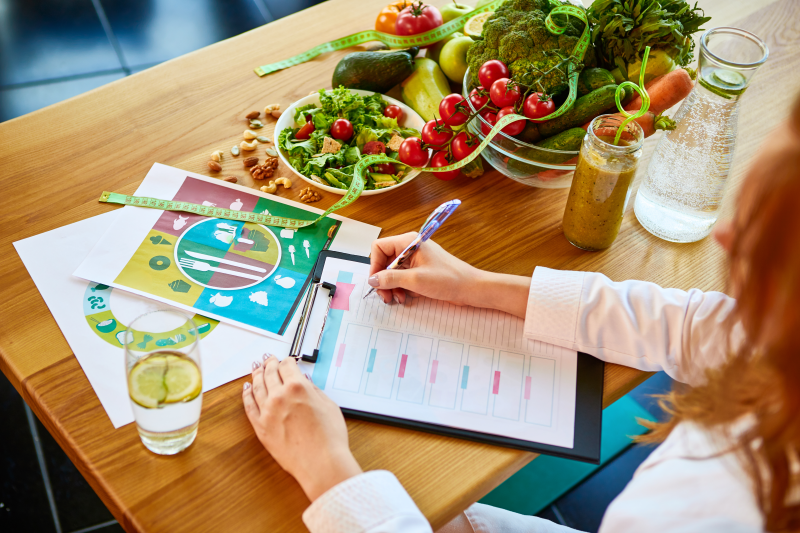 Nutritionist planning meals with vegetables and diet charts
