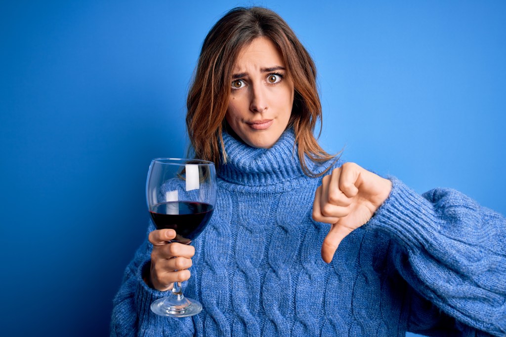 Woman thumbs down to a glass of wine