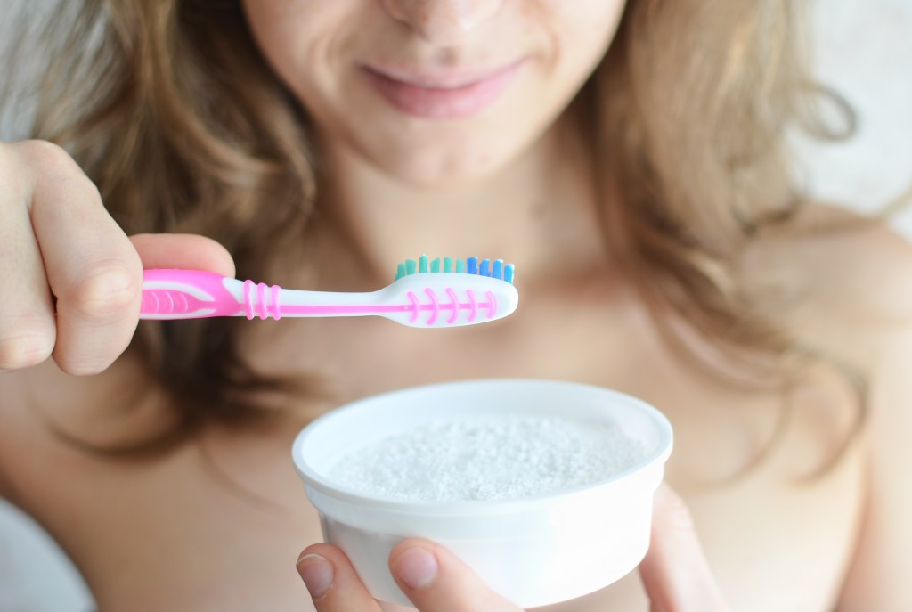 Woman brushing teeth with baking soda