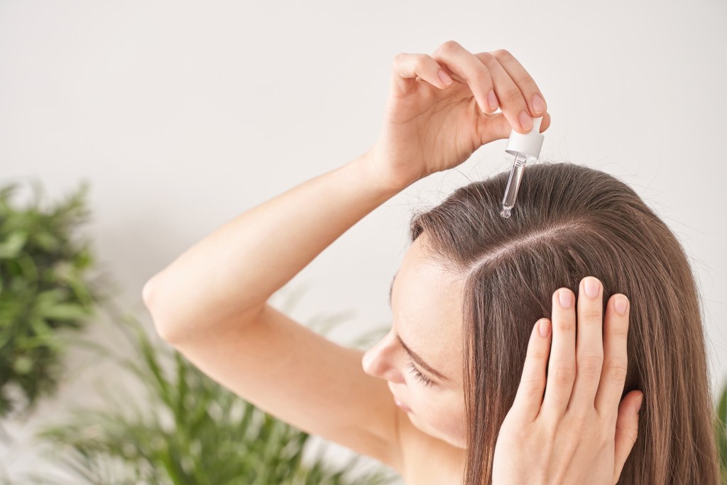 Woman applying castor oil to hair