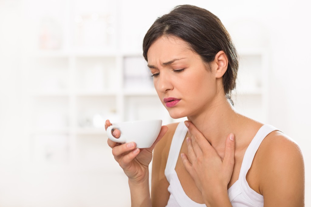 Woman with sore throat drinking warm liquids