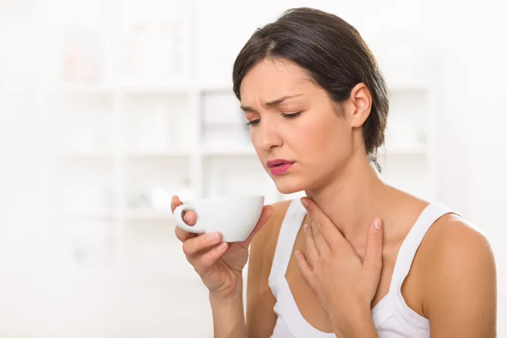 Woman with sore throat drinking warm liquids