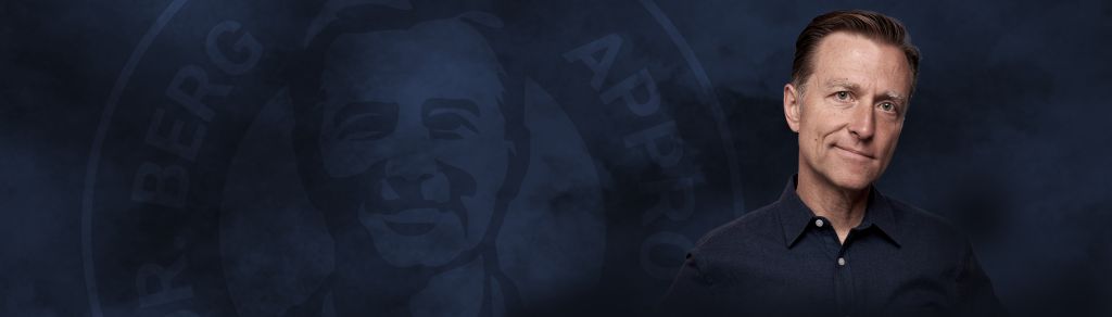 Dr. Berg smiling on a dark background