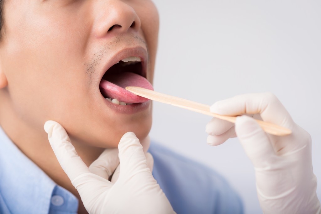 Doctor examining throat and tongue