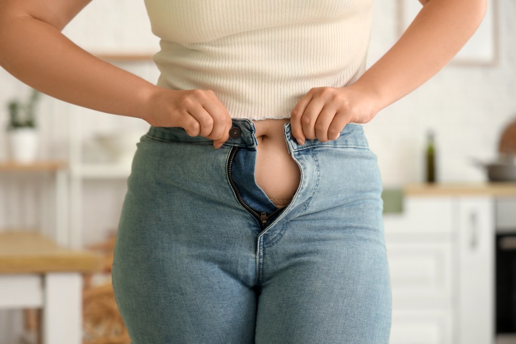 Woman trying to button pants