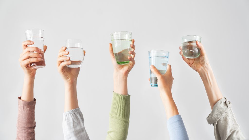 Different hands holding water glasses