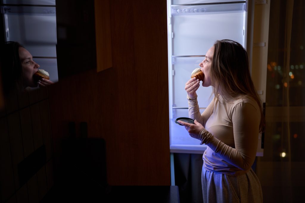 Woman eating a cupcake in pajamas
