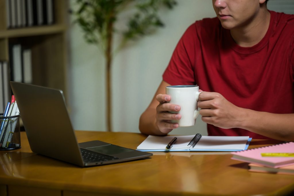 Man drinking coffee in front of laptop